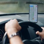 Navigator in car vehicle transportation commuter. Driver man using mobile phone navigator app while driving car